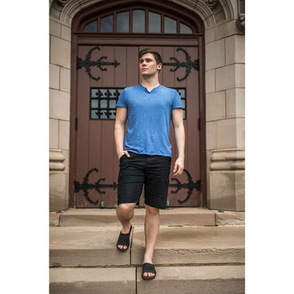 PowerStep Orthotic Arch Supporting Slide Sandals for Men, man standing on stairs with building and doorway in the background while wearing black slide sandals with arch support